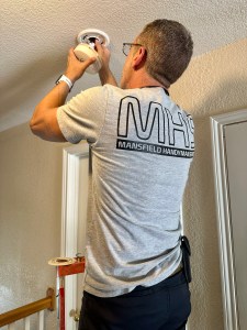 Technician installing smoke detector on ceiling in Mansfield TX